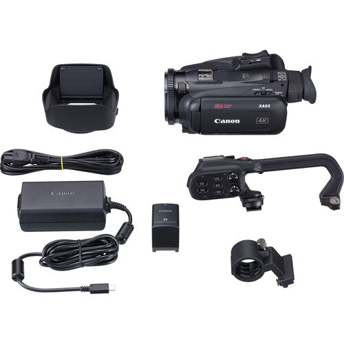Complete kit layout of the Canon XA65 4K camcorder with top handle, battery pack, power adapter, cables and microphone mount.